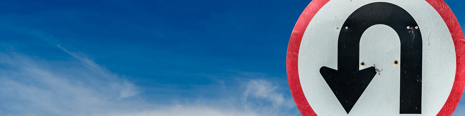 Verkehrsschild Bitte wenden vor blauem Himmel