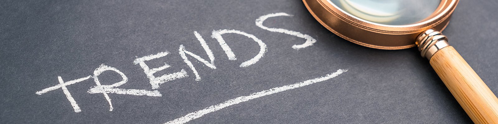 Auf einer Tafel steht Trends und daneben liegt eine Lupe